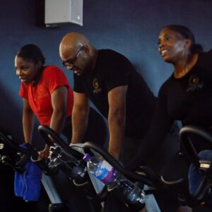 Three people are riding on stationary bikes in a gym.